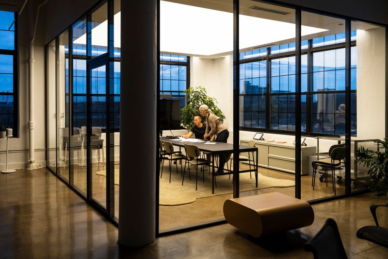 Colleagues in 20s and 50s reviewing documents at end of workday in modern office.