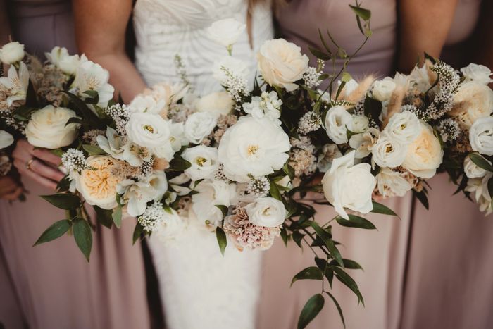 Elegant bridal bouquets with white and cream flowers held by bridesmaids in muted dresses.
