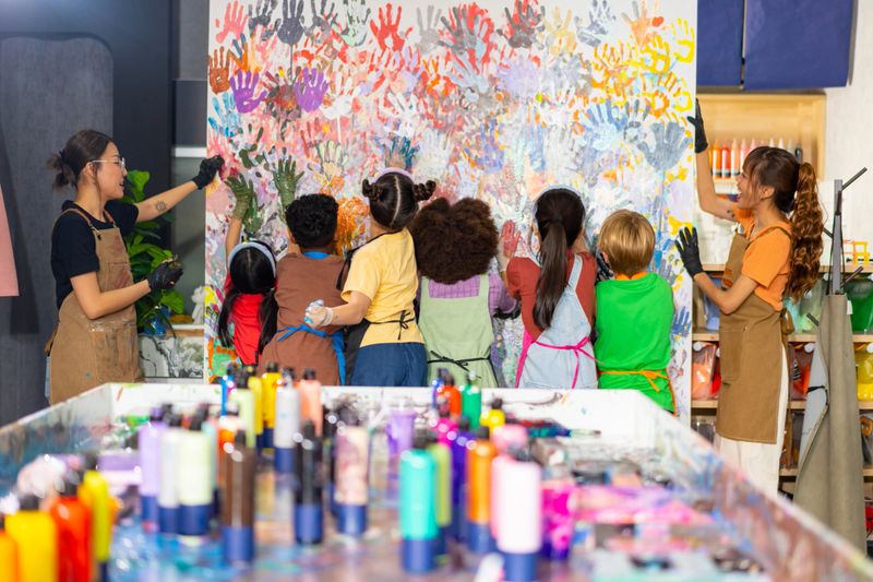 Group of Diversity school children learning acrylic art on canvas frame workshop with teacher at art studio. Happy boys and girls enjoy and fun with colorful abstract modern art painting in classroom.