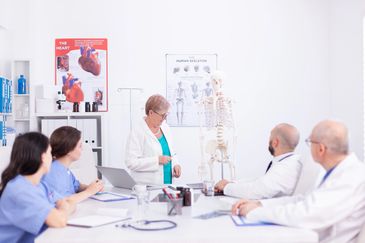 Medical professionals discussing human anatomy with a skeleton model.