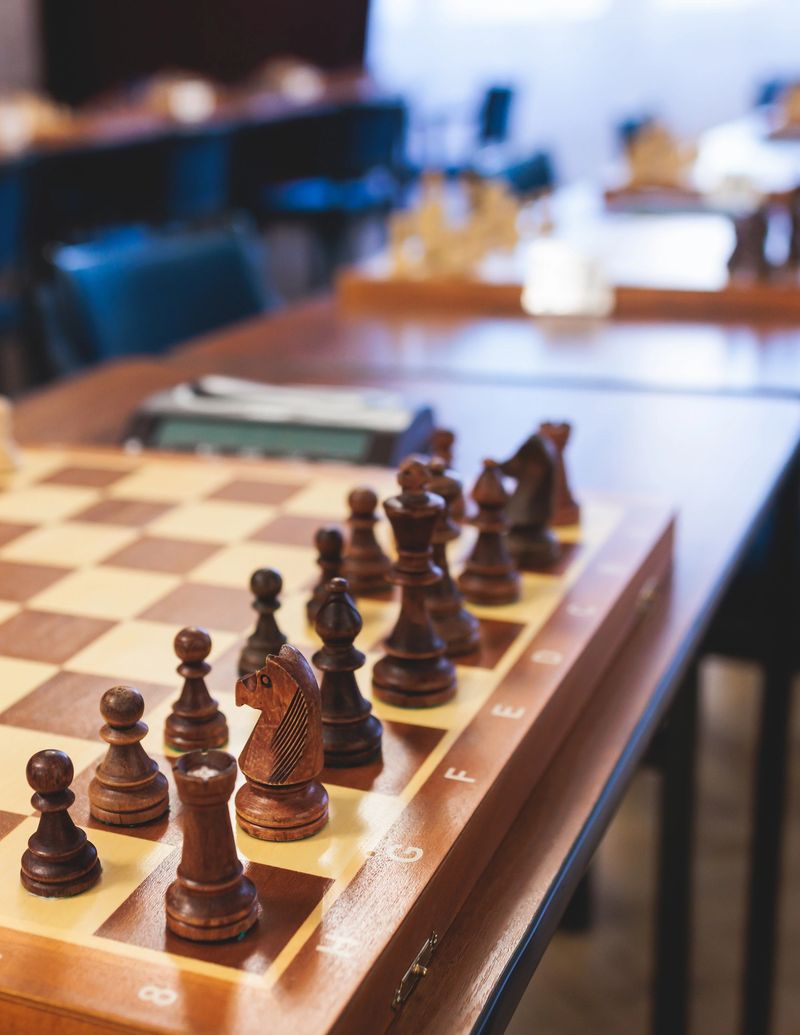 Chess tournament, kids and adults participate in chess match game outdoors in indoor hall, players of all ages play, competition in chess school club with chessboards on a table