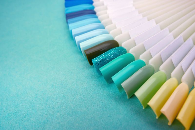 Samples of nail polish in different bright colors. Colorful manicure samples with nail polish on blue background