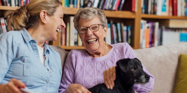 Two women laughing with a dog.