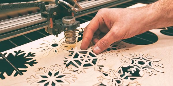 Hand cutting snowflake shapes with a laser cutter.