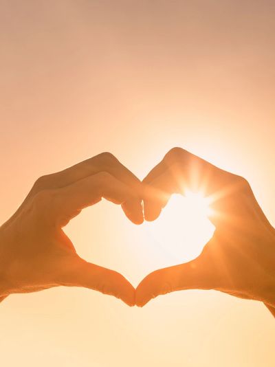Hands forming a heart shape with sunlight.