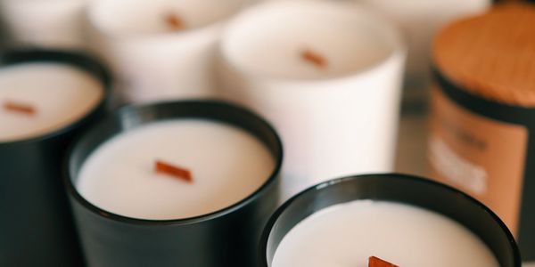 Rows of white candles in black and white containers on display.