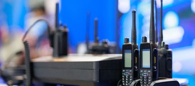 Several black walkie-talkies with antennas on a charging station.