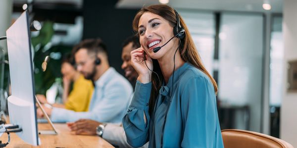 Smiling customer service representative wearing a headset at work.