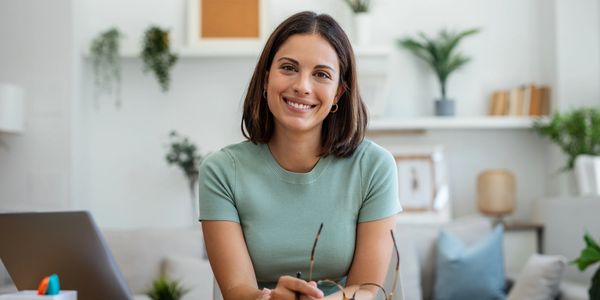 Smiling woman sitting at a table with glasses in hand.