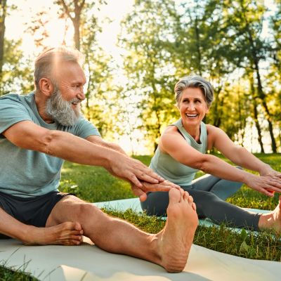 Senior couple stretching and smiling outdoors.