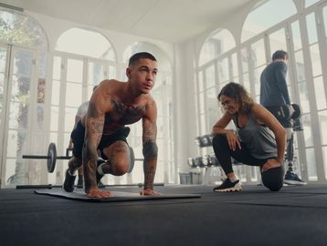 A man and woman are doing push ups in the gym.