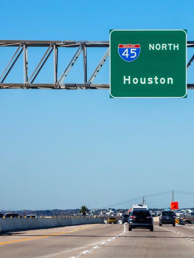 Highway sign for Interstate 45 North to Houston under clear blue sky.