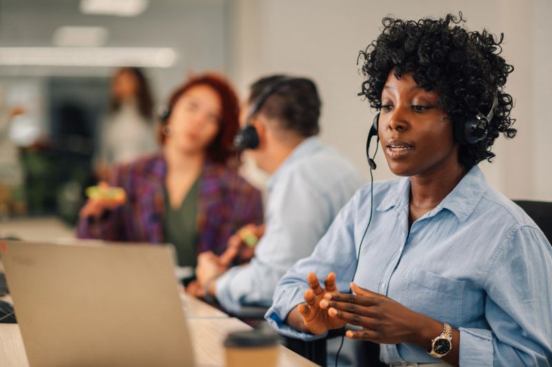 Portrait of a young african american woman working on a computer in a call center. Black female customer support executive working in an office while using a headset and a laptop. Copy space.