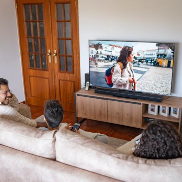 Trois personnes regardent la télévision dans un salon.