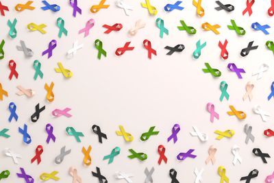 Colorful awareness ribbons forming a heart shape on a light background.