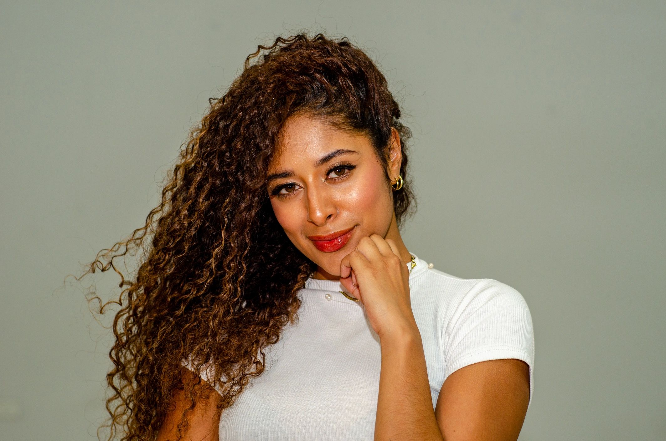 Smiling woman with curly hair and white top.