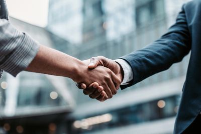 Two people shaking hands in a business setting.