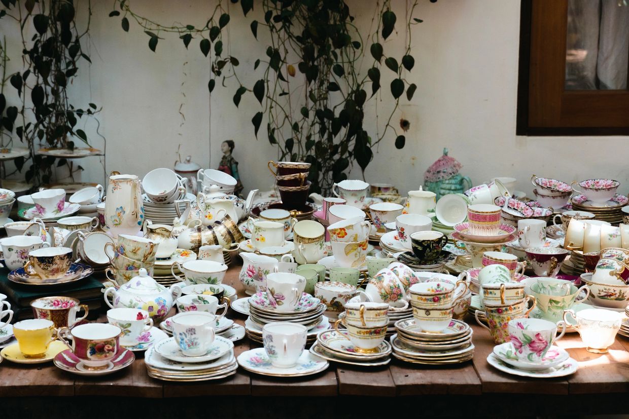 A large collection of assorted vintage teacups and saucers displayed on a table.
