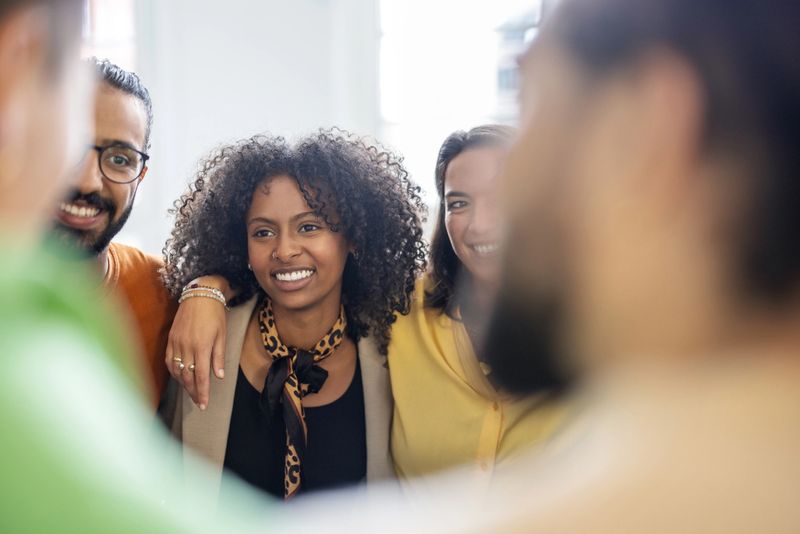 Multi-ethnic business team in a huddle in office. Group of business people standing in circle during team building session.