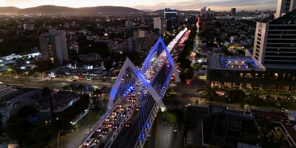 Puente peatonal iluminado en la ciudad al anochecer.