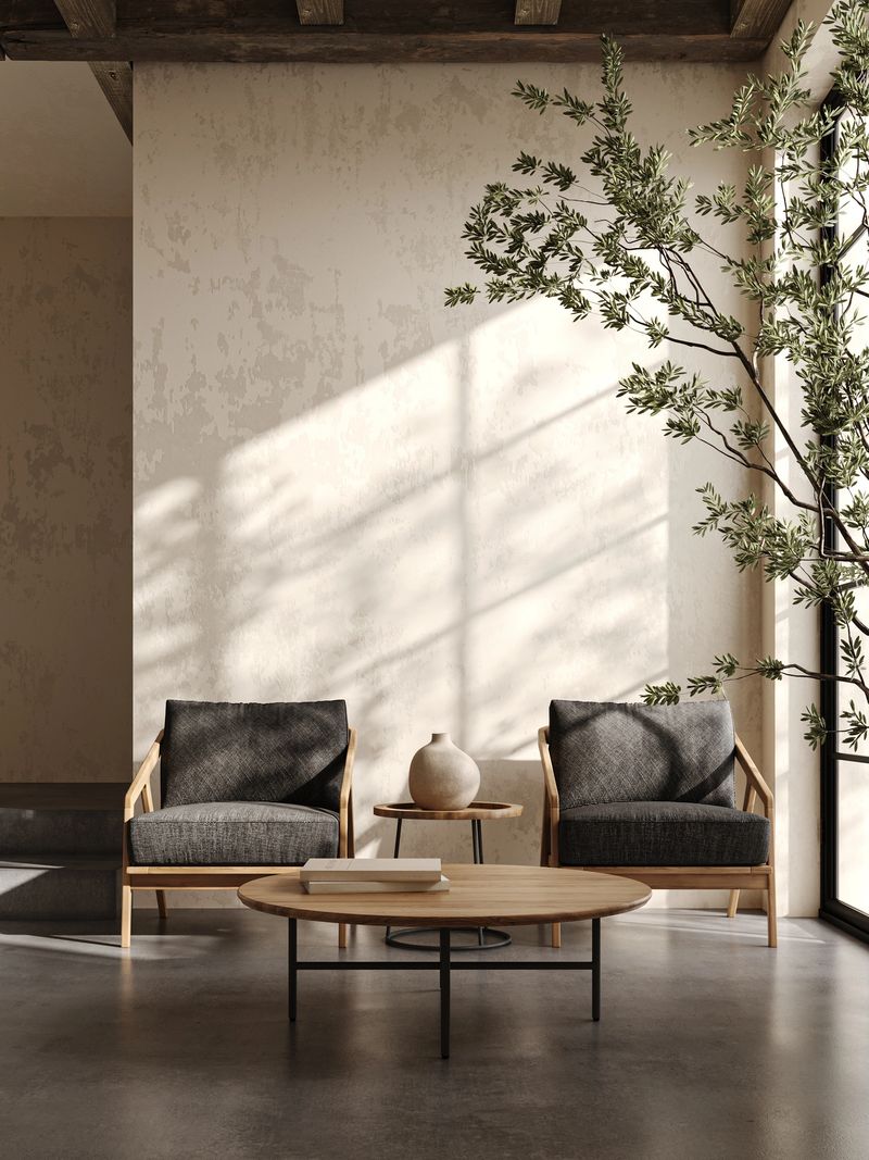 Warm sunlight bathes a contemporary living room, highlighting the chic wooden armchairs and circular coffee table that create an inviting and sophisticated atmosphere. 3d render