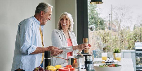 Senior couple cooking together happily in a bright kitchen.