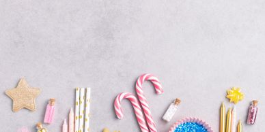 Festive holiday decorations including candy canes, candles, and glittery stars on a gray background.