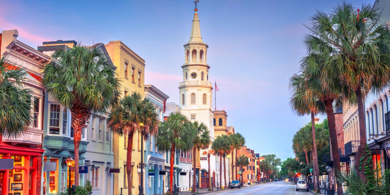Historic street with palm trees and clock tower at sunset.