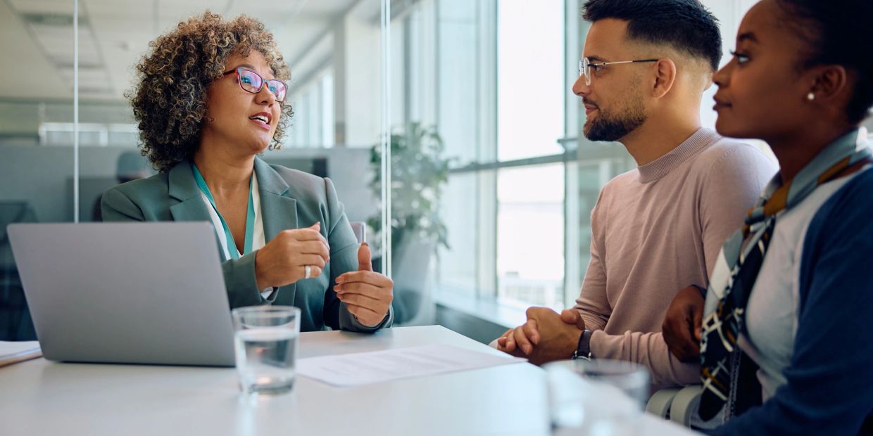 Business meeting with three professionals discussing at a table.