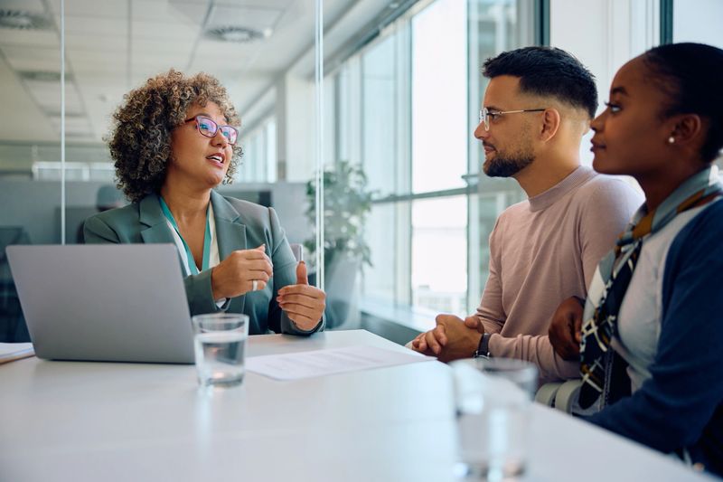 Young multiracial couple taking to financial advisor while having a meeting in the office.