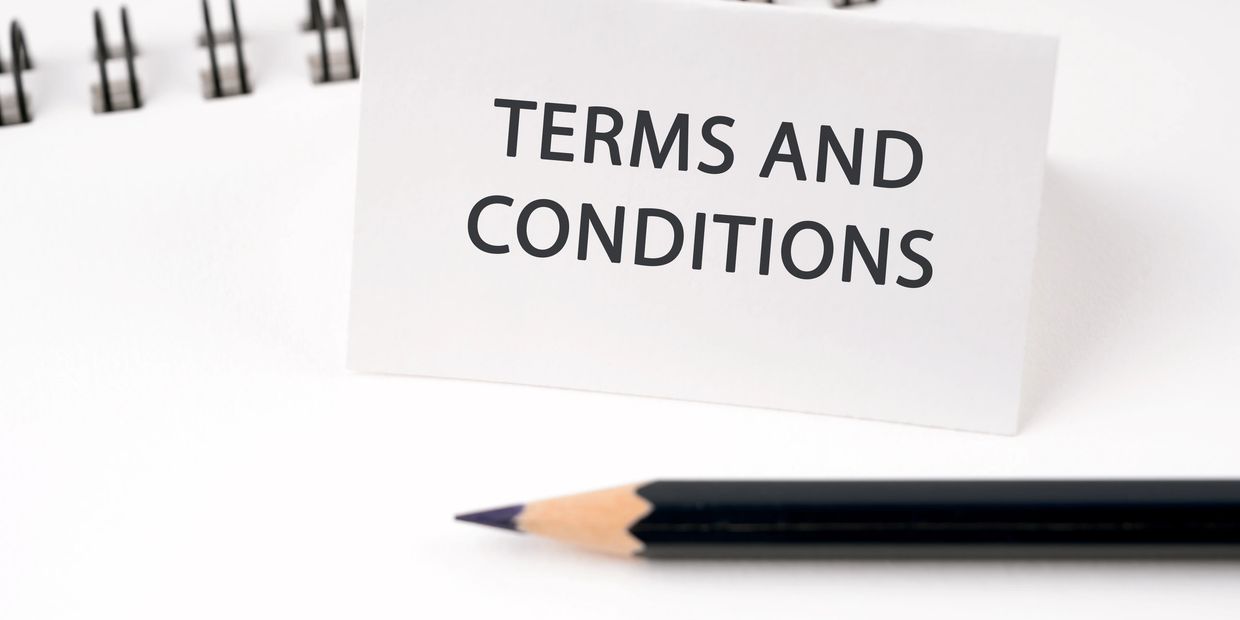 A card with 'TERMS AND CONDITIONS' text next to a pencil and a notebook.