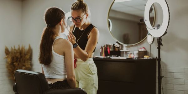 A makeup artist applying makeup to a seated client.