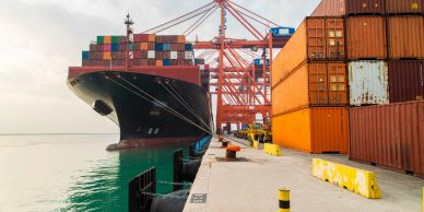 Container ship docked at port with stacked containers.