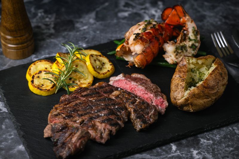 surf and turf, ribeye steak and lobster tail on black marble background