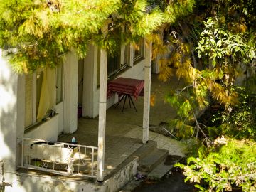 A porch with a red table surrounded by trees.