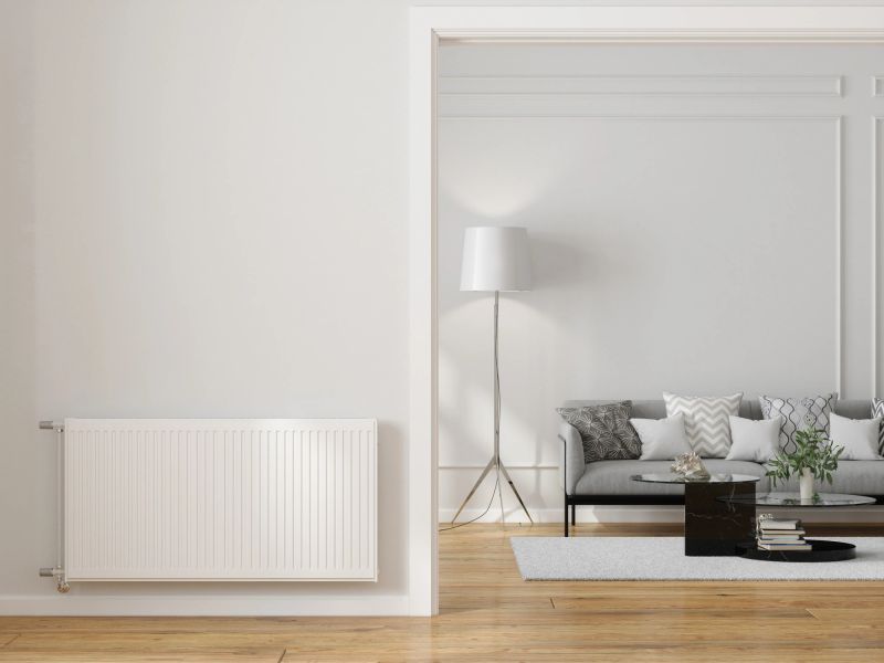 Modern Living Room Interior With Radiator On Blank Wall, Sofa, Coffee Table And Floor Lamp
