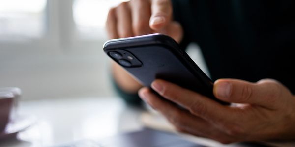 Person using a smartphone near a laptop keyboard. Carpet Cleaning process, Pet-Friendly Cleaning, Residential Cleaning FAQs