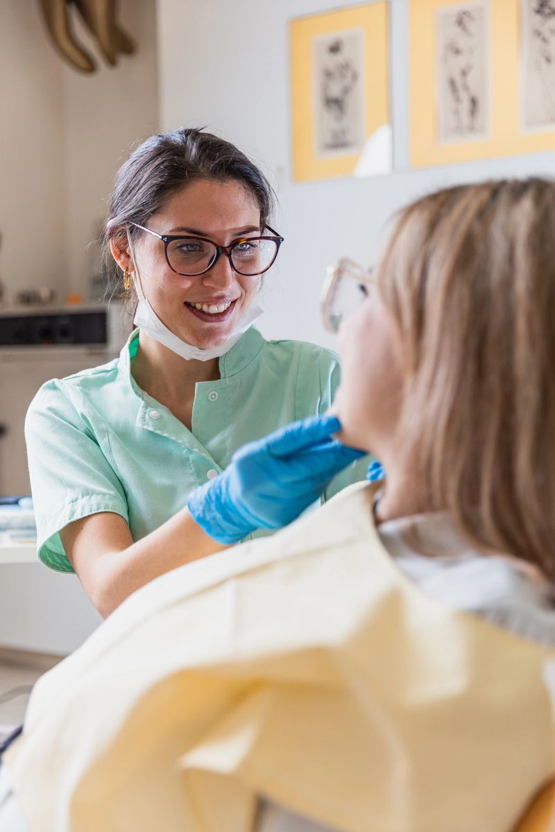 The young dentist and the female patient are happily smiling after a dental procedure in the office