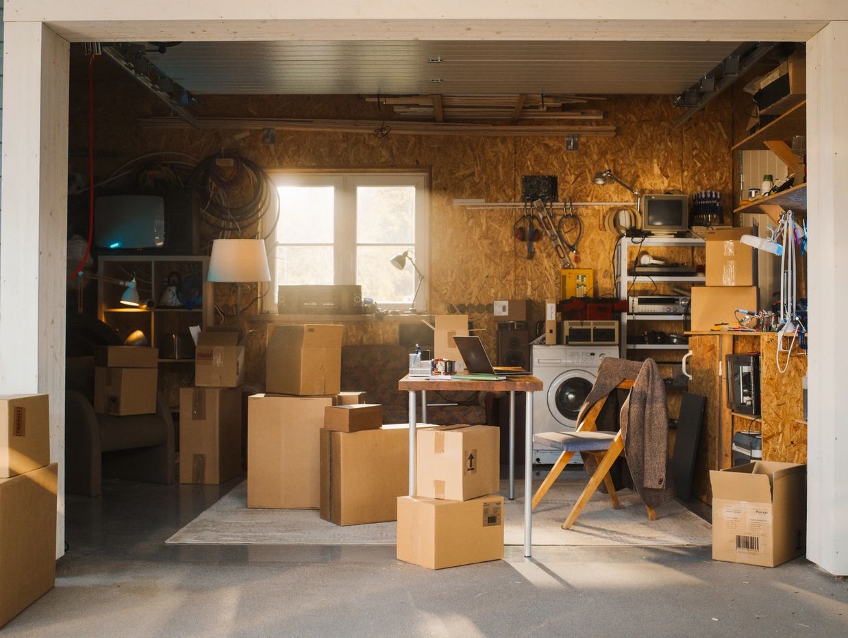 A cluttered garage with boxes and a laptop on a table.