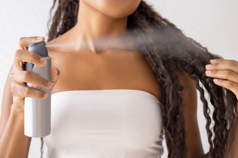 Woman putting hairspray on her hair