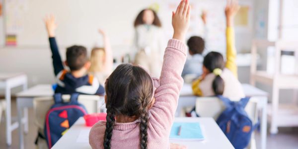 Students raising hands in classroom.
