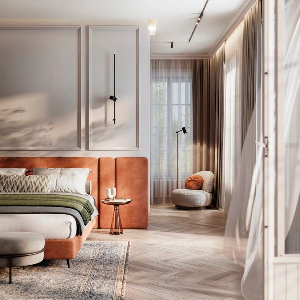 Sunlit modern bedroom with rust-colored bed and cozy reading nook.