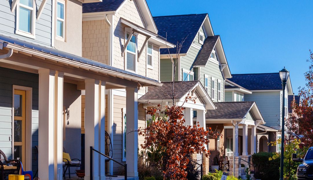 Row of suburban houses with porches under a clear blue sky.