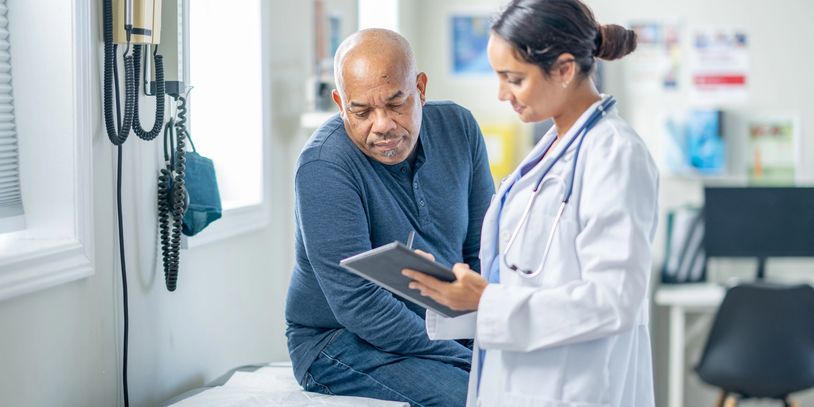 Doctor consulting with an elderly male patient in a clinic.