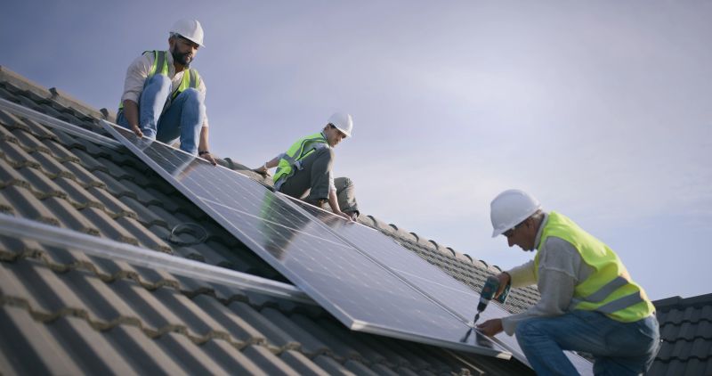 Engineer group, rooftop and solar panel with construction team, development or sustainability for electricity. People, support or help with drill for photovoltaic tech on roof, ecology or environment