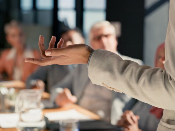 Person gesturing while speaking at a meeting.