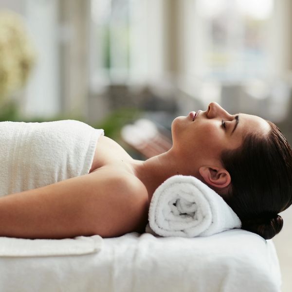 Woman relaxing on massage table with towel under neck.