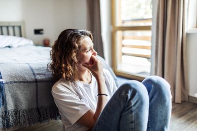 Woman sitting on the floor looking thoughtful.