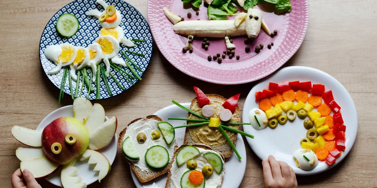 Creative animal shapes made from fruits, vegetables, and bread on plates.