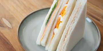 Three triangular sandwiches with different fillings on a plate.